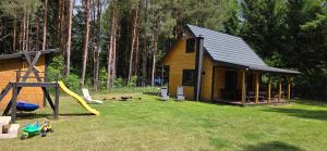 a log cabin with a slide and a playground at Leśne Zacisze 3 in Łuka
