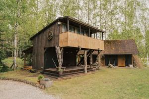 a large wooden house in the middle of a forest at Beachside Guest House Piejuras nams in Ķesterciems