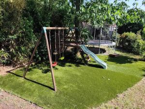 a playground in a yard with a swing at Le Chêne Vert - Grande Villa familiale avec piscine - Bassin d'Arcachon in Arès