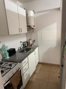 a small kitchen with white cabinets and a sink at Depto Céntrico cq in Bahía Blanca