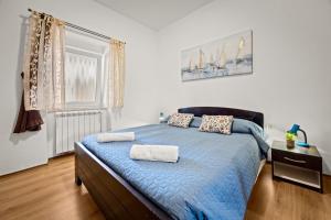 a bedroom with a blue bed with two towels on it at Pool Apartments Franko - Shared Pool in Ližnjan +53 photos