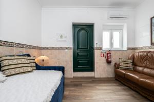 a bedroom with a green door and a bed and a couch at Casa da Muralha in Beja