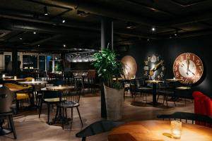 ein Restaurant mit Tischen und Stühlen und einer Uhr an der Wand in der Unterkunft Ruby Claire Hotel Geneva by IHG in Genf