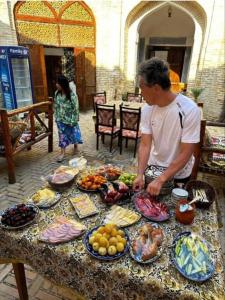 a man standing in front of a table of food at Caravan Sarai XV century Mextar Ambar old town in Bukhara