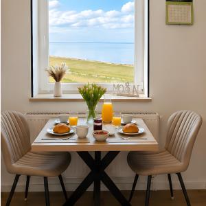 a table with plates of food on it in front of a window at Gaestehaus Nuke in Langeneß