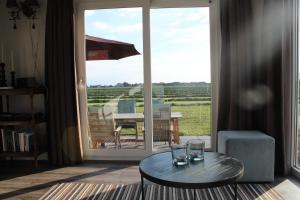 a living room with a table and a view of a field at Chalet vrijheid in Tjerkgaast