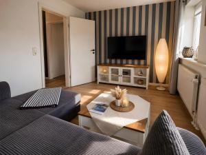 a living room with a couch and a tv at Gaestehaus Nuke in Langeneß