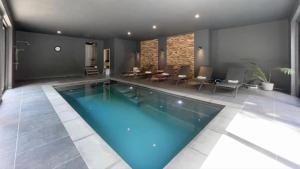 a large swimming pool in a room with chairs and tables at Villa Damseaux in Spa
