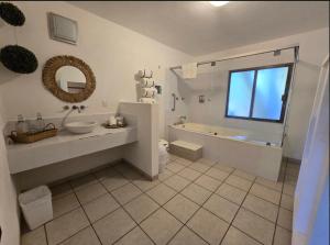 a bathroom with a tub and a sink and a mirror at Eco Taboutique Hotel & Cabañas in Monte Gordo