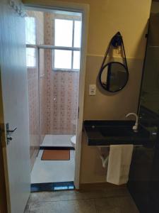 a bathroom with a shower and a sink and a mirror at Loft Campinho 3 in Estação Inhoaíba