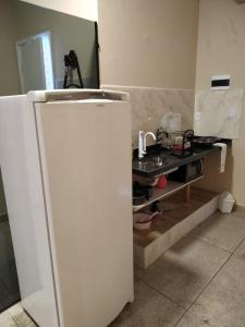 a kitchen with a white refrigerator and a sink at Loft Campinho 3 in Estação Inhoaíba