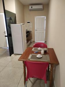 a table with two red chairs and a refrigerator at Loft Campinho 3 in Estação Inhoaíba