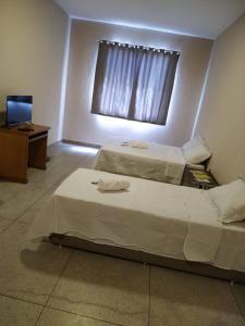 a bedroom with two beds and a television and a window at Loft Campinho 3 in Estação Inhoaíba +4 photos