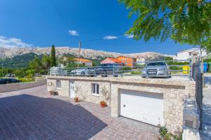a garage with two white garage doors in a parking lot at Apartments Mia in Baška