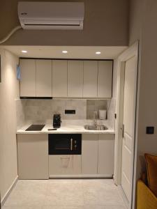 a small kitchen with white cabinets and a sink at Aggeliki Apartment in Skiathos