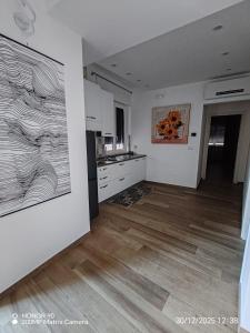 a kitchen with white cabinets and a wooden floor at Rooms 2,6 in Terlizzi