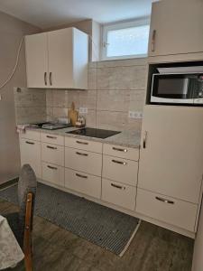 a kitchen with white cabinets and a microwave at Ágnes Apartmanok in Harkány +14 photos