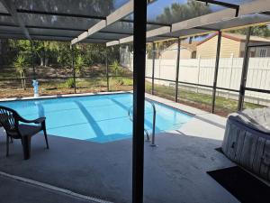 a swimming pool with a table and a chair next to it at Home Away from Home with Heated Pool in New Port Richey