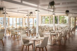 a dining room with tables and chairs and windows at Electra Beach Holiday Village in Ayia Napa