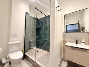 a bathroom with a toilet and a glass shower at The Siding Apartments in Hilton