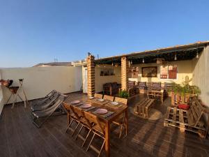 a patio with a wooden table and chairs on a roof at Happy Waves Morocco - Surf Hostel Tamraght in Tamraght Ou Fella