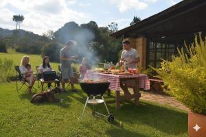 a group of people standing around a barbecue grill at Chalet Casa de Teja in Tinjacá