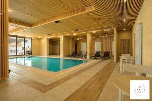 a pool in a building with chairs and a table at Green apartment Velingrad in Velingrad