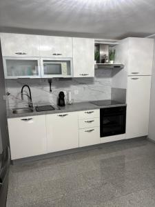 a white kitchen with a sink and a microwave at Matea in Plomin