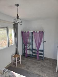 a room with a bed with purple curtains and a chair at Maset Paradiso in Vanacloig