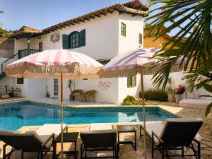 a pool with chairs and umbrellas next to a house at Elsi Pousada in Búzios