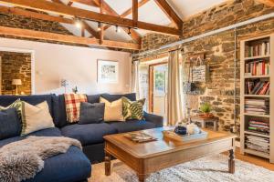 a living room with a blue couch and a wooden table at Shippon in Michaelstow