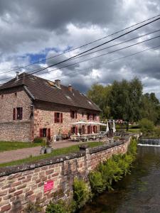 a building next to a river with a stone wall at Relais du Moulin - Bed & Breakfast in Abreschviller