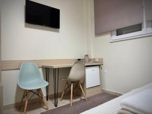 a room with two chairs and a desk with a television at Guest House Nova in Mostar