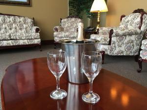 a table with two wine glasses and a bucket with a bottle at Motel Cofotel in Saint-Siméon