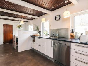a kitchen with white cabinets and a black counter top at 4 star holiday home in Aabybro in Åbybro