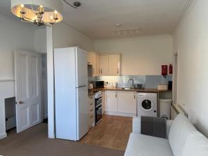 a small kitchen with a white refrigerator and a couch at Glenrigh House - The Garden Flat in Fort William