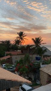 a sunset over a city with palm trees and the ocean at Sunsand Beach Suítes e Hostel in Camocim +12 photos