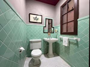 a green bathroom with a toilet and a sink at Sereno Hostels in Bogotá