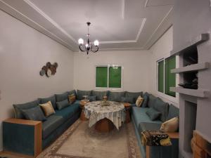 a living room with a blue couch and a table at عين السلطان ain sultan in Imouzzer du Kandar