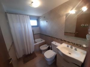 a bathroom with a white toilet and a sink at Reflejo de Mar in Villa Gesell +12 photos