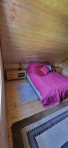 a bed in a wooden cabin with a purple comforter at Chatka Puchatka in Gołubie