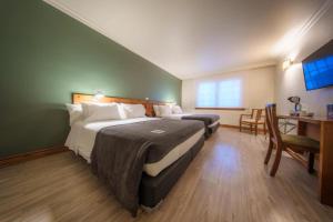 a hotel room with two beds and a desk and a table at Almasur Punta Arenas in Punta Arenas