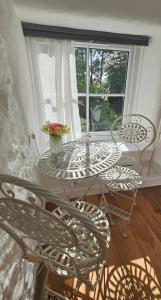 a table and chairs in a room with a window at Primrose Cottage peaceful room and private garden in Helston +20 photos