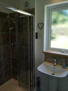 a bathroom with a shower and a sink and a window at Hawk Hill in Rosemarkie