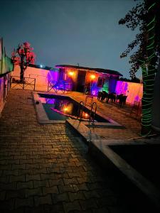 a night view of a building with purple lights at Mandys Farm House in Manjhāoli