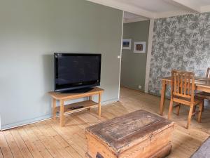 a living room with a flat screen tv and a wooden table at Gästhus Vejbystrand in Vejbystrand