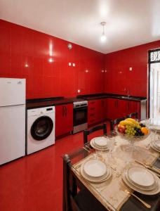 a red kitchen with a table with a bowl of fruit at APART HOTEL KOBULETi in Kobuleti
