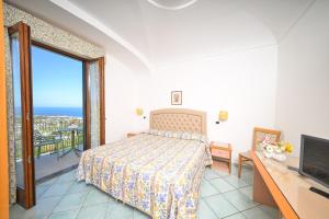 a bedroom with a bed and a tv and a balcony at La Capannina - Hotel & Apartments in Ischia Town