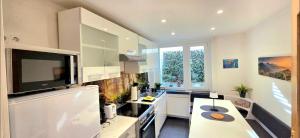 a kitchen with white cabinets and a tv on the wall at Ferienhaus Harzblick in Bischofferode
