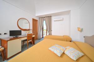 a hotel room with two beds and a desk and a mirror at La Capannina - Hotel & Apartments in Ischia Town +77 photos